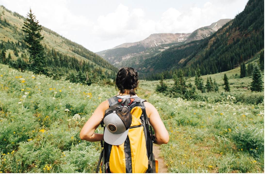 Woman hiking in the mountain with a yellow backpack.
